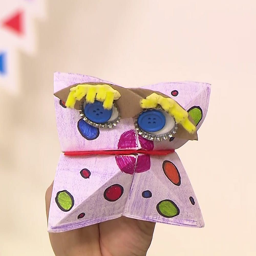 Ağzı kapalı pembe benekli tuzluk kukla, sarı yün kirpikli mavi düğme gözleriyle önden