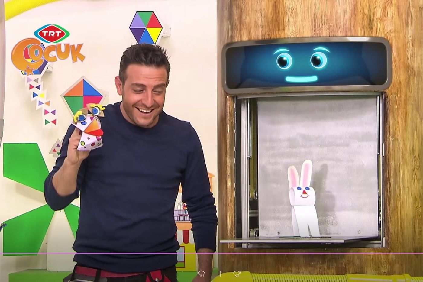Programdan kare: sunucu elindeki tuzluk kuklayı oynatıyor, yanındaki bölmede kağıt tavşan