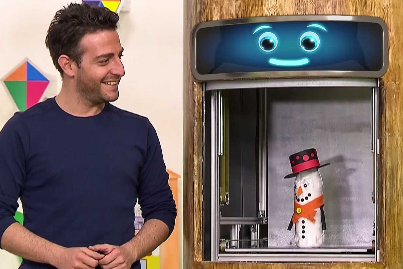 Televizyon programından kare: sunucu stüdyoda, yanındaki pencerede şişeden kardan adam duruyor