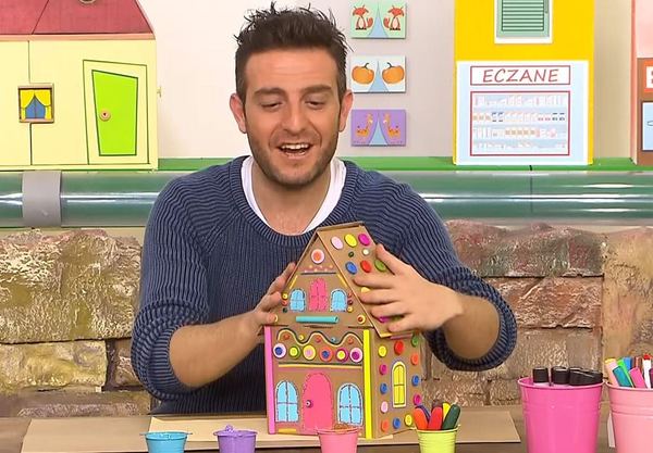 Şeker ev yayın karesi: sunucu renkli düğme ve şekerlerle süslenmiş karton evi gösteriyor