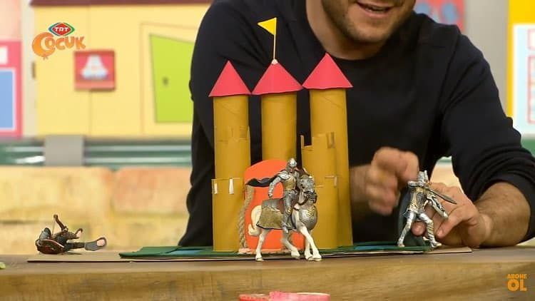 Yayından kare: sunucu rulo şatonun önünde oyuncak şövalye ve atla oynuyor
