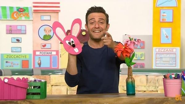 Çiçek Buketi programından kare: sunucu pembe tavşan el kuklasını ve vazodaki kağıt çiçekleri gösteriyor