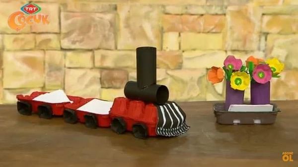 Tren notluk: yumurta kolisinden kırmızı-siyah boyalı lokomotif ve not kağıtlı vagonlar, yanda çiçekli kalemlik