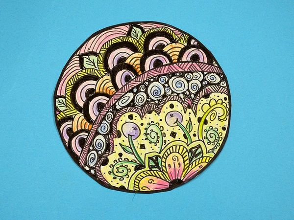 Desen topu çizgi terapi çalışması: daire içine çizilmiş spiral, yaprak ve çiçek desenleri pastel tonlarda boyanmış, yakın çekim