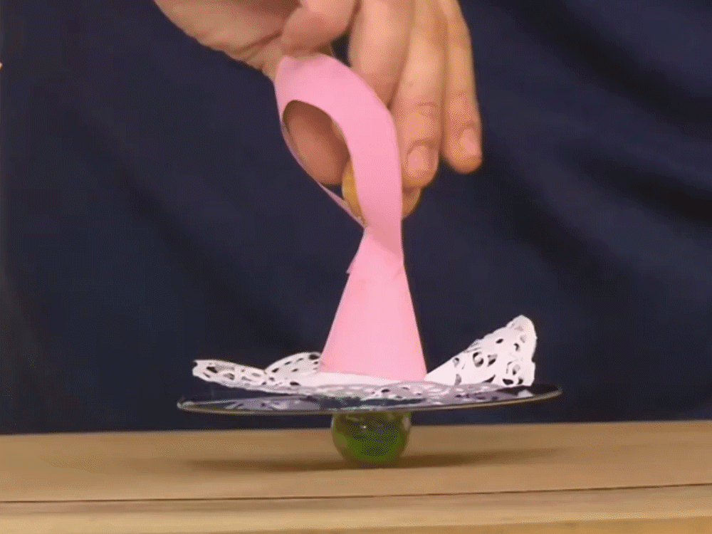 Pembe kağıt balerini tepesinden tutarak CD tabanlı fırıldağı çeviren parmaklar