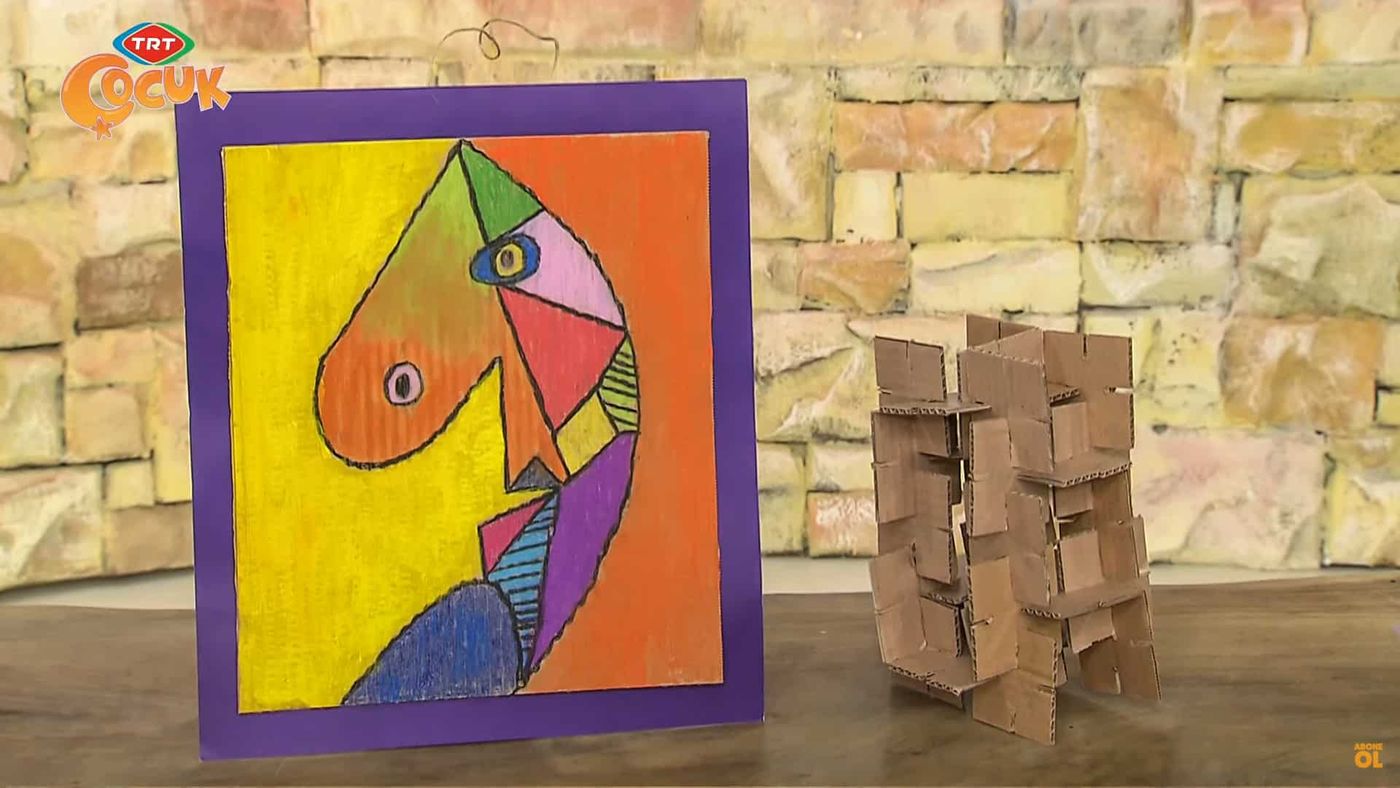 Taş duvar önünde Picasso tarzı renkli portre ve yanında geçmeli mukavva heykel