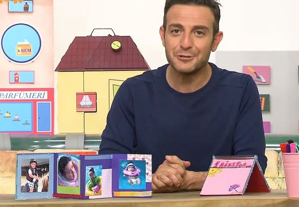 Mini yaz albümü: programdan kare, sunucu masadaki fotoğraflı akordeon albümü ve pembe kartı gösteriyor