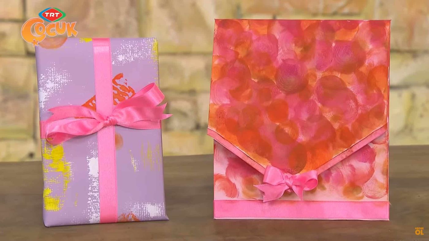Baskılı leylak paket ile turuncu-pembe benek baskılı, kurdeleli kağıt zarf yan yana
