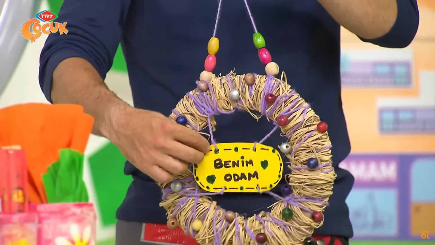 Benim Odam levhalı rafya çelenk boncuk dizili iple asılarak gösteriliyor