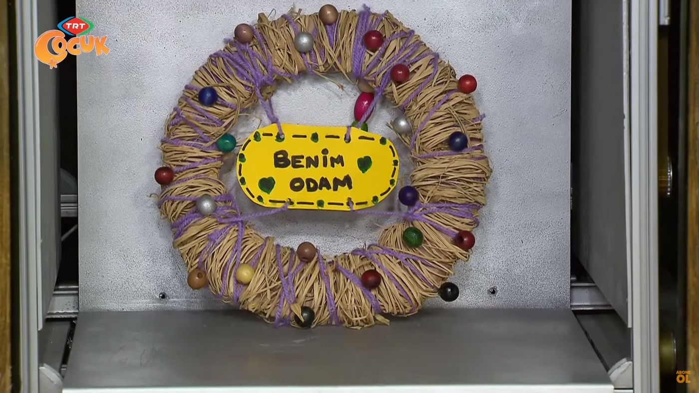 Rafya sarılı, renkli boncuklu halka çelenk, ortasında sarı Benim Odam yazılı kapı levhası