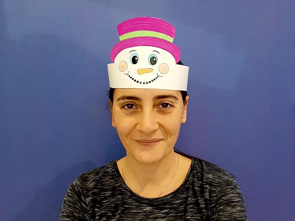 Pembe şapkalı kardan adam tacı bir yetişkinin başında, mor fon önünde