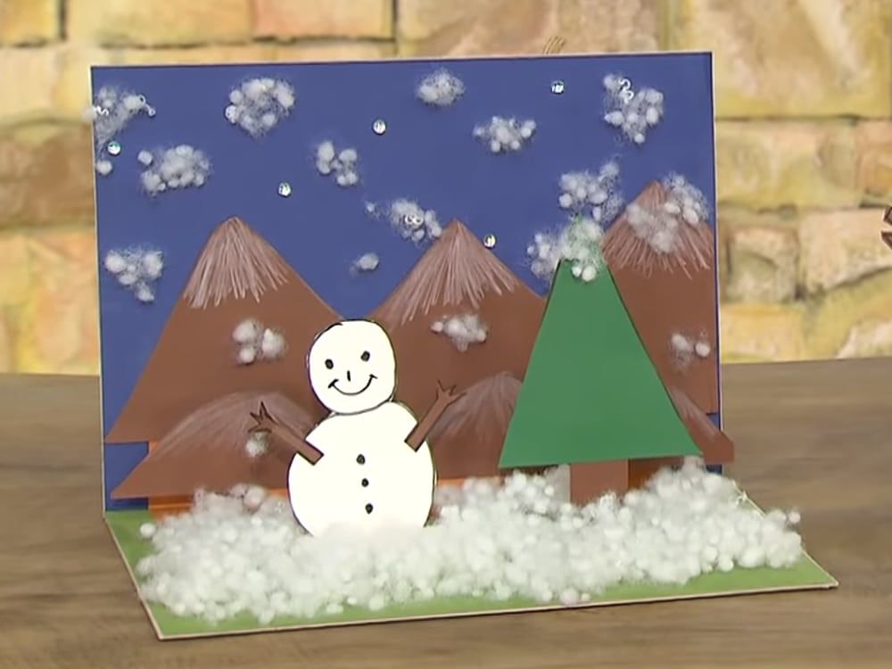 3D kış resmi: kartondan dağlar ve çam ağacı, kardan adam, pamuk kar ve mor gökyüzünde kar taneleri
