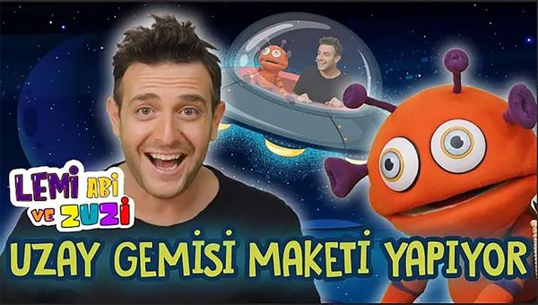 Uzay gemisi yapımı videosunun kapağı: sunucu, turuncu uzaylı kukla ve tabaktan uzay gemisi maketi