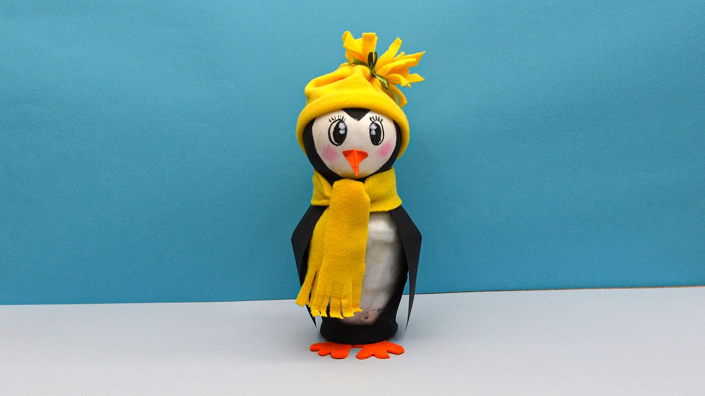 Mavi fon önünde sarı bereli ve atkılı kavanoz penguenin daha uzaktan önden görünümü