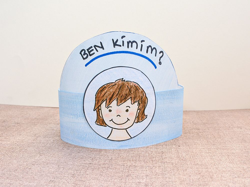 Ben Kimim? kağıt taç: mavi boyalı şerit üstünde başlık yazısı ve daire içinde çizilmiş çocuk yüzü